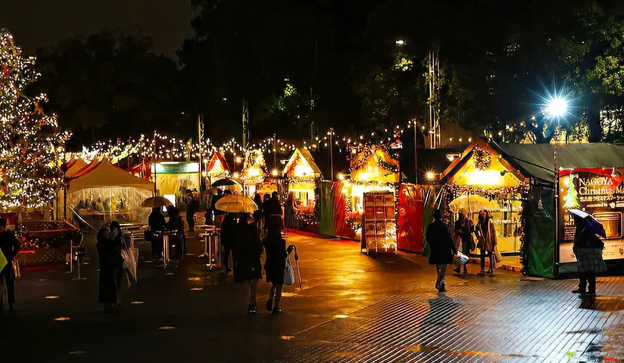 Wooden Christmas market stalls lit with warm lights at the Nagoya Christmas Market in Hisaya Odori Park, Nagoya, Japan.